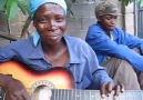 Beautiful African Woman Plays Guitar In A Slightly Non-Traditional Manner )