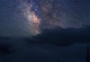 The milkyway peacefully glides above the clouds on a warm summer night