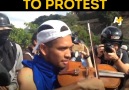Venezuelan musicians play the violin while police tear gas protesters.